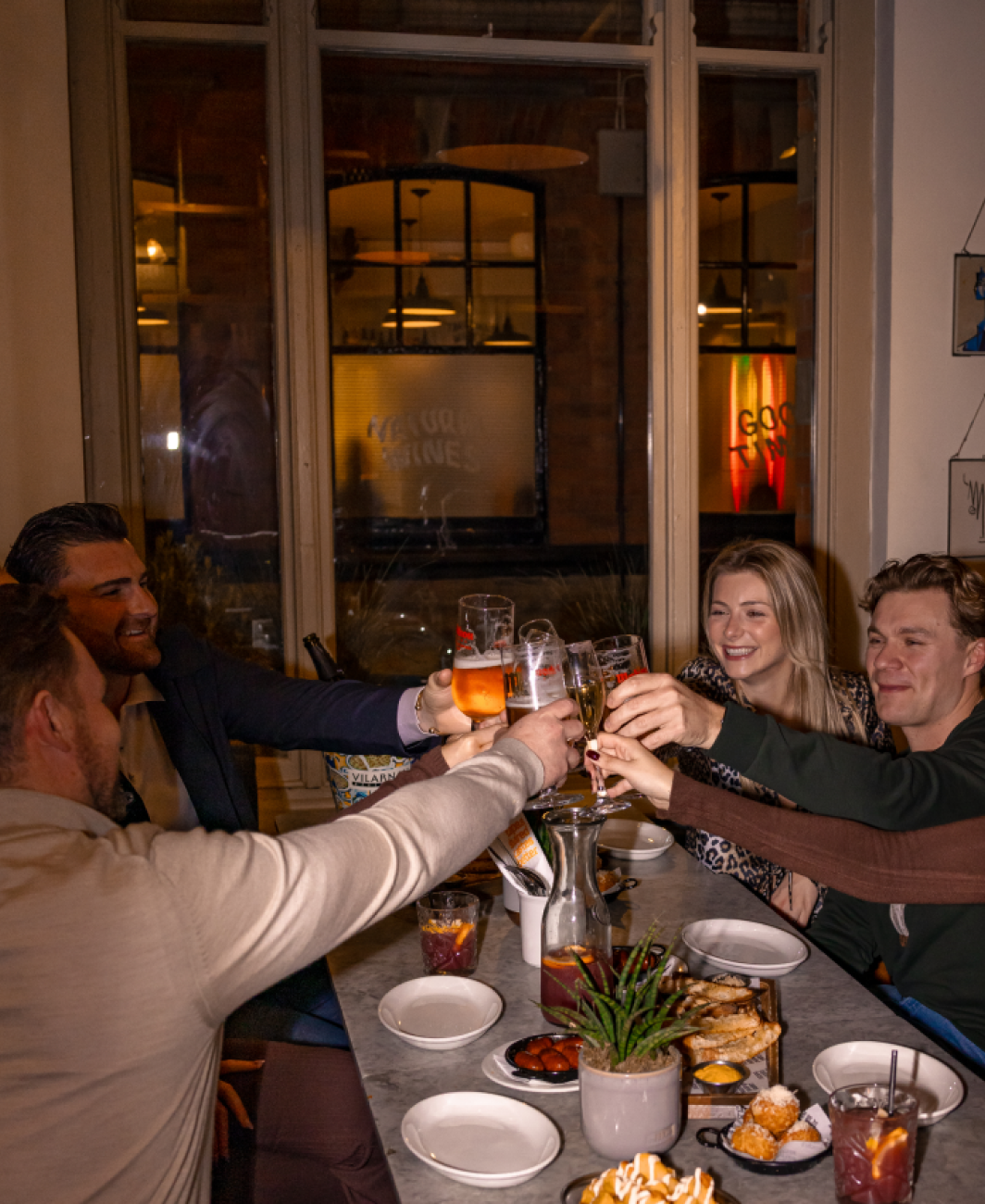 Friends raising glasses around a Baresca table